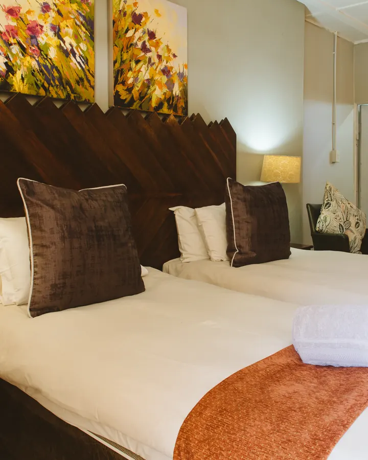 A BIWEDA twin room with two single beds beneath a carved wooden headboard