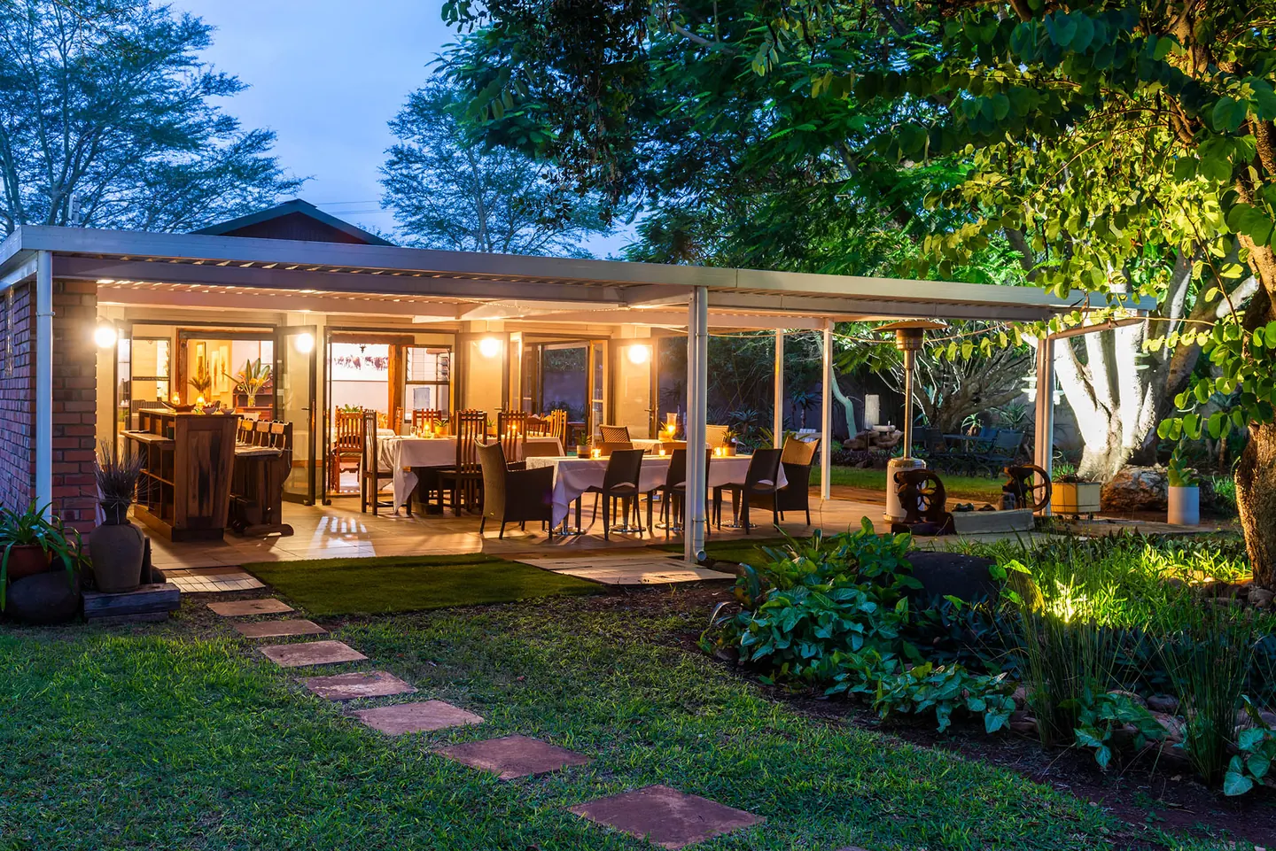 A stepping-stone path across the lawn to BIWEDA's lodge, its veranda lit up at dusk