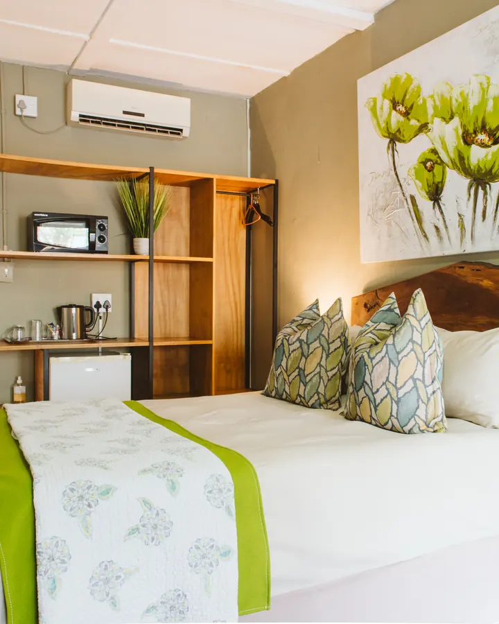A BIWEDA double room with a made-up double bed, botanical artwork and a tea and coffee station